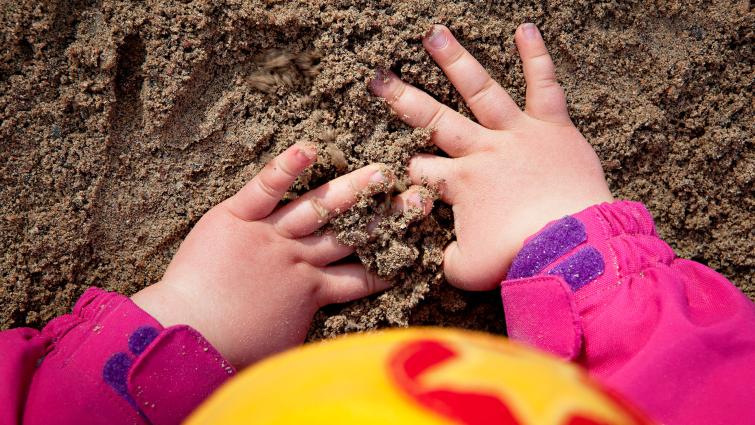 Lapsen kädet hiekassa