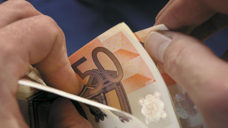 Lähikuva käsistä selaamassa viidenkymmenen euron seteleitä. Kuva: Pixhill.