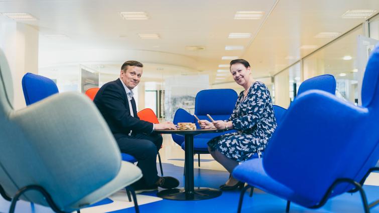 Lahden kaupungin toimitilajohtaja Jouni Arola ja henkilöstöjohtaja Mira Keitaanranta istumassa sinisillä nojatuoleilla pöydän ääressä.